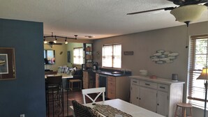 A spacious kitchen with a dining area, a ceiling fan, and a view of the living room.