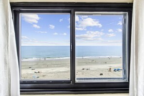 A view of a beach through a window with a black frame.
