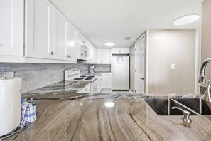 A modern kitchen with white cabinets, a marble countertop, a built-in oven, and a stainless steel sink. - *Fall into Savings-20% Off New Bookings thru 2026* (Garden City)