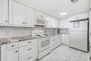 A kitchen with white cabinets, a stove, a microwave, and a refrigerator. - *Fall into Savings-20% Off New Bookings thru 2026* (Garden City)
