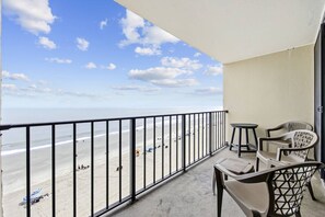 A balcony with a view of the beach, a table, two chairs, and a small round table. - *Fall into Savings-20% Off New Bookings thru 2026* (Garden City)