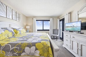 A hotel room with a bed, a television, a chair, and a view of the ocean. - *Fall into Savings-20% Off New Bookings thru 2026* (Garden City)