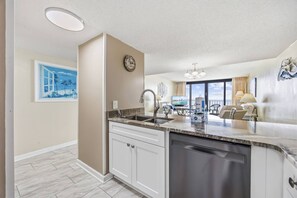 A modern kitchen with a dishwasher, a sink, and a dining area with a table and chairs. - *Fall into Savings-20% Off New Bookings thru 2026* (Garden City)