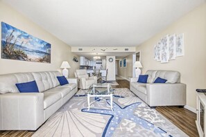 A living room with two sofas, a coffee table, and a rug. There is a kitchen in the background. - *Fall into Savings-20% Off New Bookings thru 2026* (Garden City)