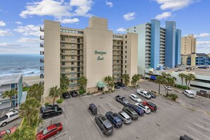 A multi-story hotel with a parking lot in front, located near a beach. - *Fall into Savings-20% Off New Bookings thru 2026* (Garden City)