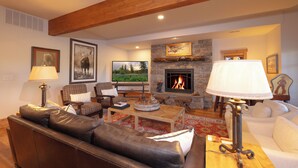 A cozy living room with leather sofas, a fireplace, and a television. - Salmonfly Lodge Remodeled Teton Springs Log Cabin in Victor w/ Hot Tub & A/C (Victor)