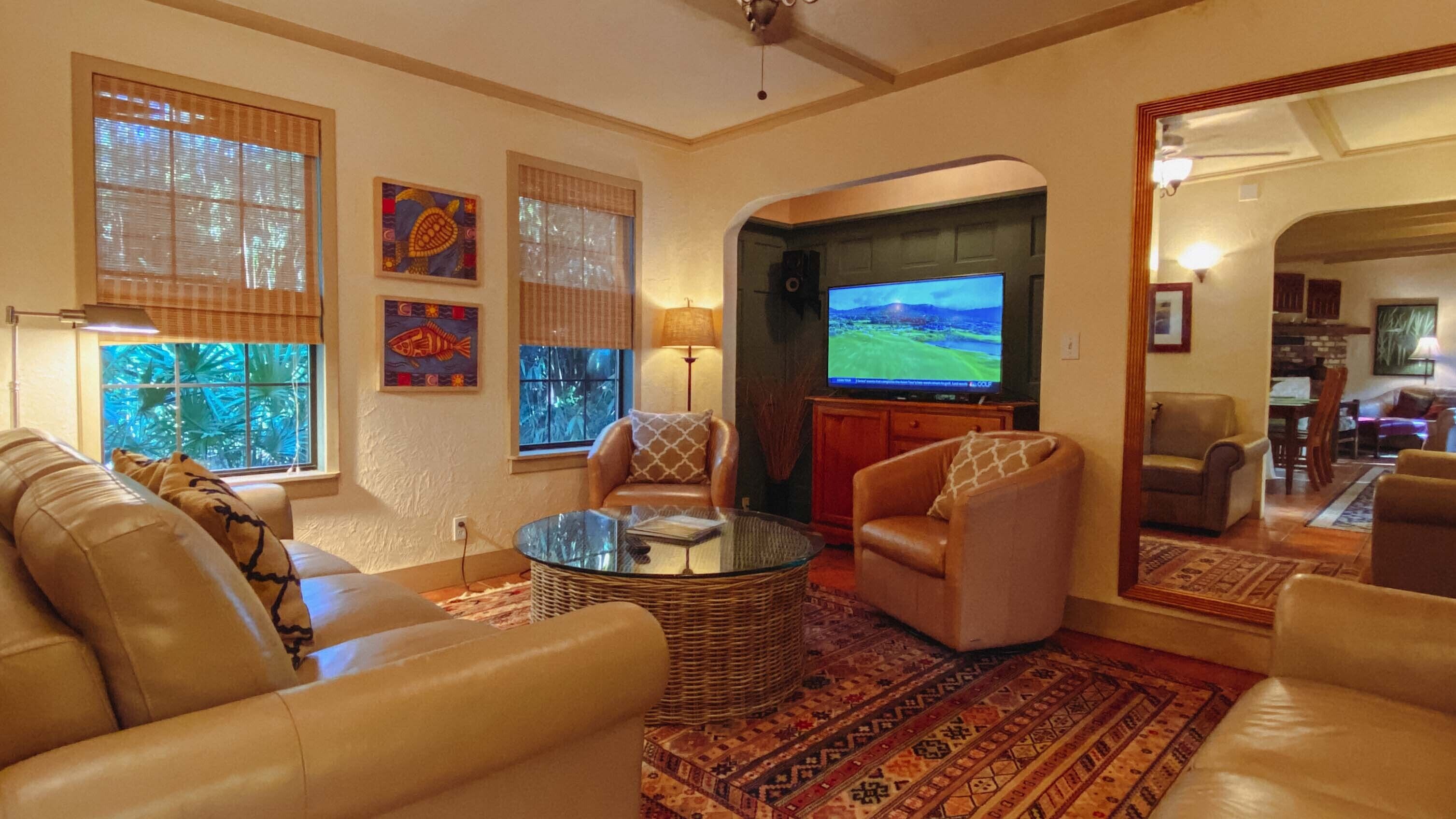 A living room with leather sofas, a glass coffee table, and a television.