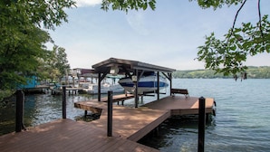 A wooden dock extending into calm water, with a covered boat house and a bench. Boats are docked in the background. - Wine to Water - Family Adventure on Keuka Lake Awaits! (Hammondsport)