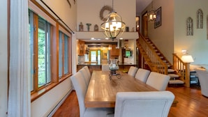 A dining area with a wooden table and chairs, a chandelier, and a staircase leading to another level. - Wine to Water - Family Adventure on Keuka Lake Awaits! (Hammondsport)