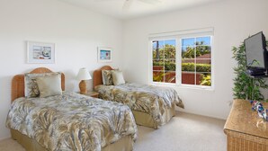 Un dormitorio con dos camas, televisión y ventana con vistas a zonas verdes.