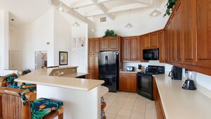 Una cocina moderna con armarios de madera, un refrigerador negro, un microondas y una estufa.