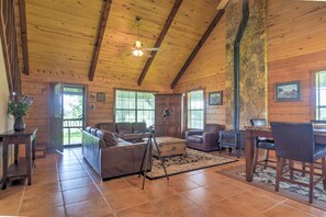 Uma sala de estar ampla com teto de madeira, lareira e parede de destaque em pedra.
