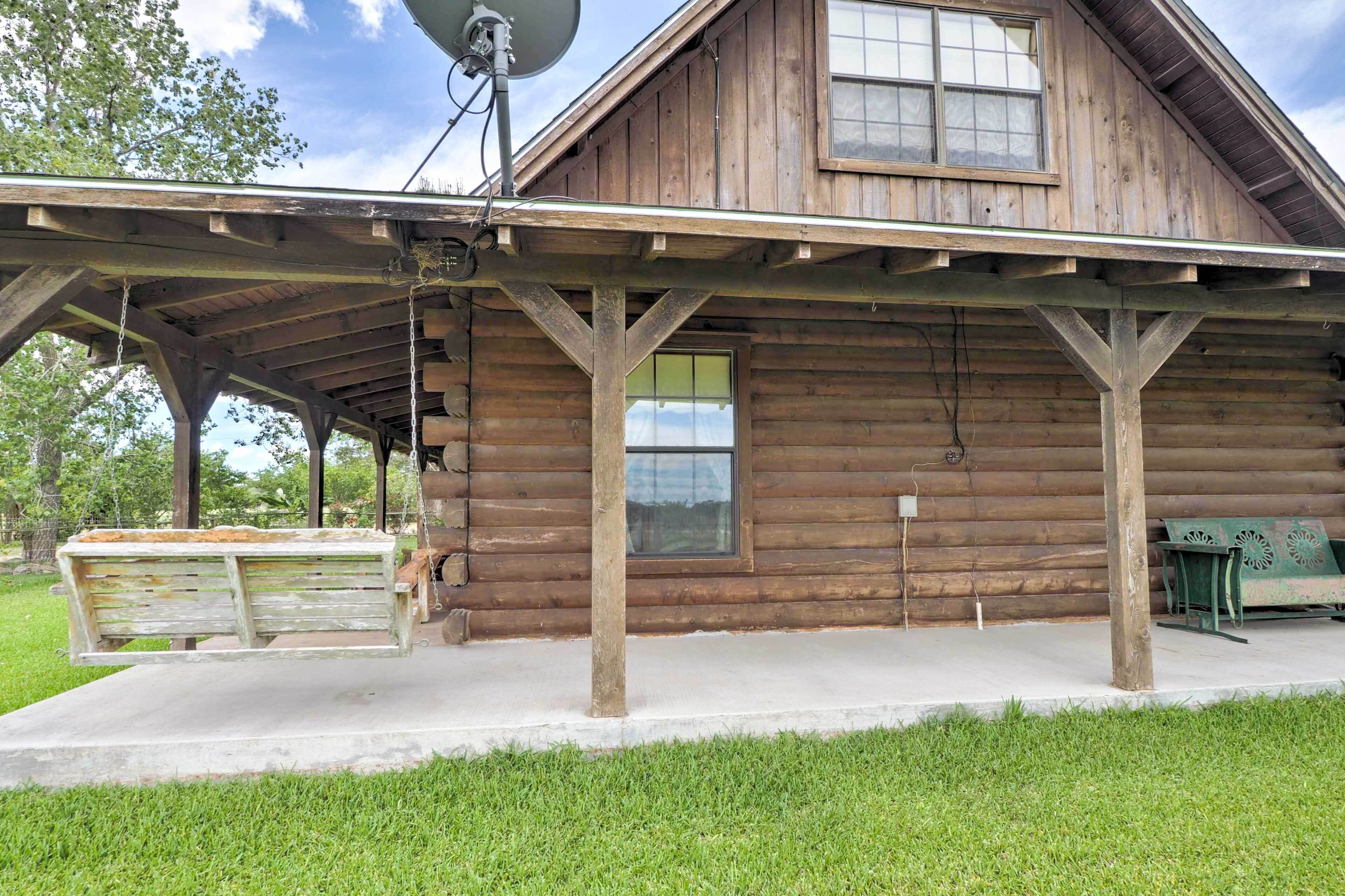 Eine rustikale Holzhütte mit überdachter Veranda, Satellitenschüssel und einer Bank.