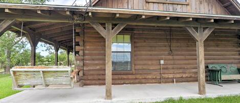 Eine rustikale Holzhütte mit überdachter Veranda, Satellitenschüssel und einer Bank.