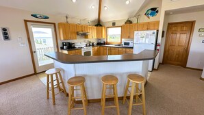 Una cocina con armarios de madera, una isla central con taburetes, un microondas y un refrigerador.
