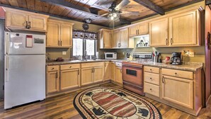 A kitchen with wooden cabinets, a refrigerator, a microwave, and a stove. - Deck + Fire Pit: Family Cabin in Bessemer (Bessemer)