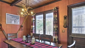 A wooden dining table with a red and black checkered table runner, two candles, and a lantern. - Deck + Fire Pit: Family Cabin in Bessemer (Bessemer)