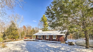 A cabin with a snow-covered ground, surrounded by trees, and a clear sky. - Deck + Fire Pit: Family Cabin in Bessemer (Bessemer)