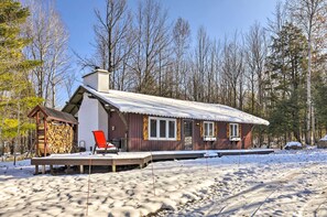 A cabin with a deck, a red chair, and a stack of firewood. - Deck + Fire Pit: Family Cabin in Bessemer (Bessemer)