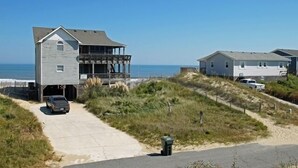 Une propriété située en bord de mer, comprenant une maison à deux étages dotée d’un porche couvert et d’un garage.