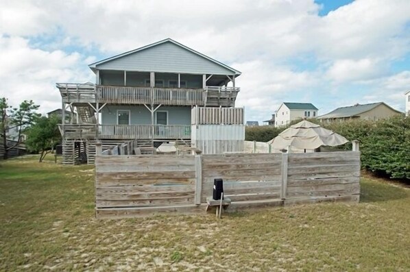 A two-story house with a balcony, surrounded by a wooden fence and a small shed. - SN8608- Semi-OF! 4 BRs, Great Views, Private Pool & Basketball! (Nags Head)