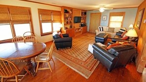 Un salon spacieux avec une table à manger en bois, des sièges confortables et un téléviseur.