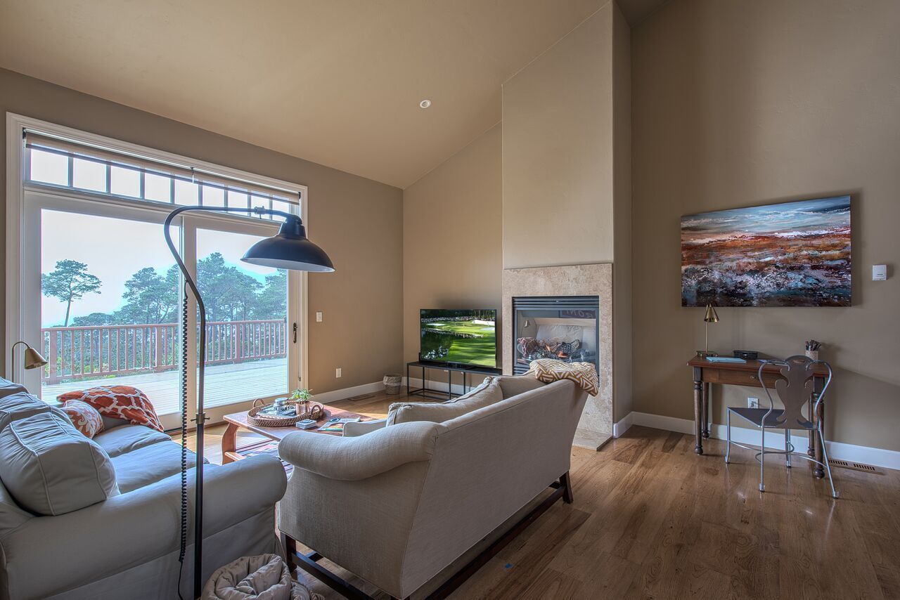 Un salón amplio con un gran ventanal, un televisor de pantalla plana, una chimenea y un cuadro en la pared.