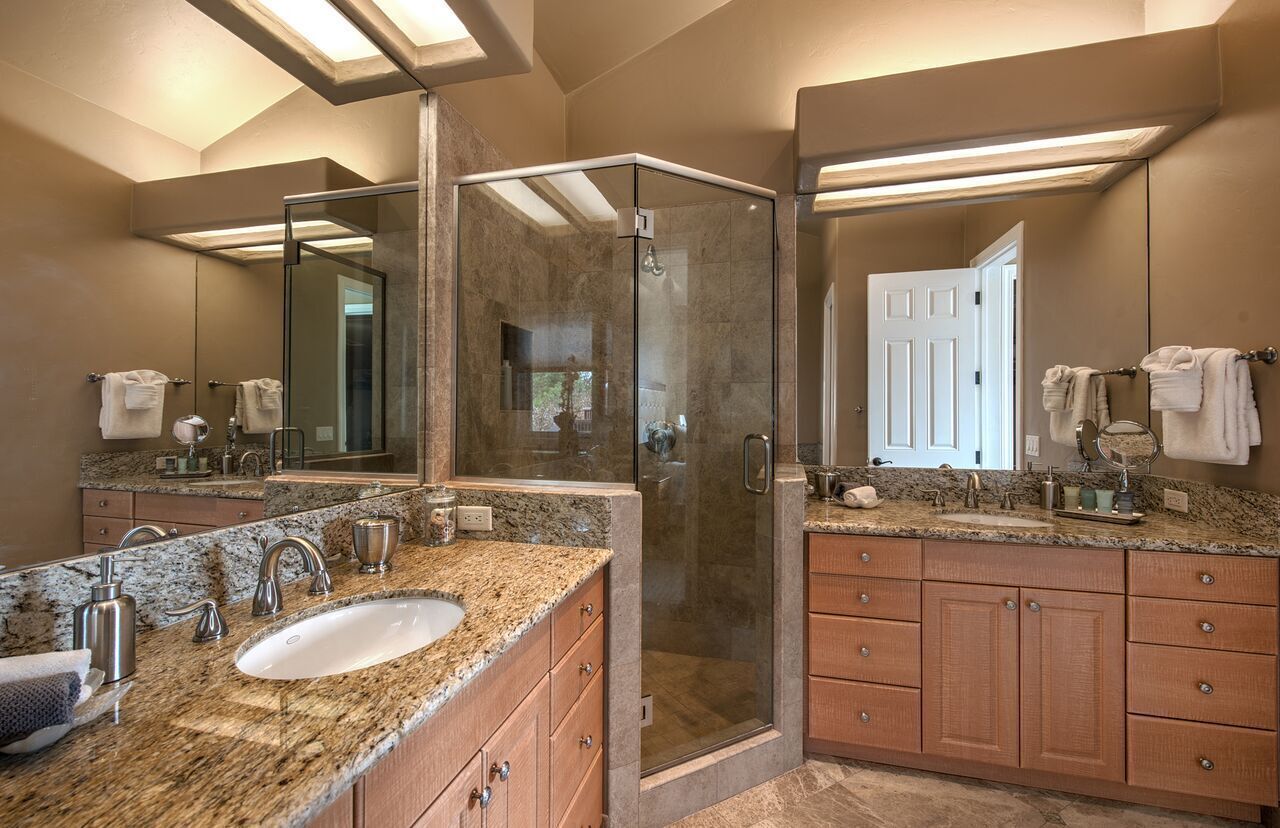 A modern bathroom with a glass-enclosed shower, granite countertops, and wooden cabinets.