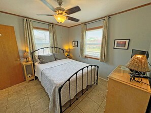 A neatly arranged bedroom with a bed, bedside lamps, a ceiling fan, and a desk with a lamp. - KD2709- Oceanfront-3 BRs (One Master), Dog Friendly, Outstanding Ocean Views! (Kill Devil Hills)
