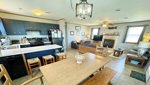 Una cocina moderna con una isla central, sillas de madera, una mesa de comedor y una chimenea en la zona de estar.