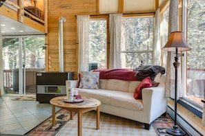 Interior acogedor de una cabaña con sofá, mesa y lámpara.