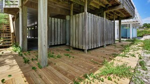 Una terraza de madera con cercado de madera y una escalera que lleva a una zona cubierta.