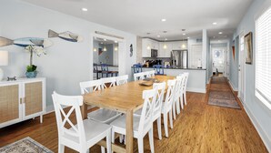 Una cocina moderna con armarios blancos, una mesa de comedor de madera y sillas blancas.