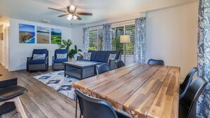 Una habitación amplia con una mesa de comedor de madera, sillas tapizadas en azul, un sofá y un ventilador de techo.