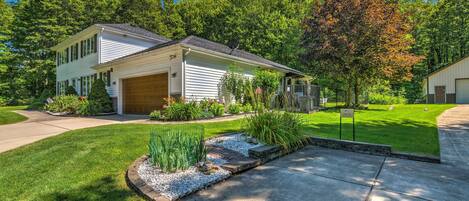 A two-story house with a garage, surrounded by a well-maintained lawn and garden.
