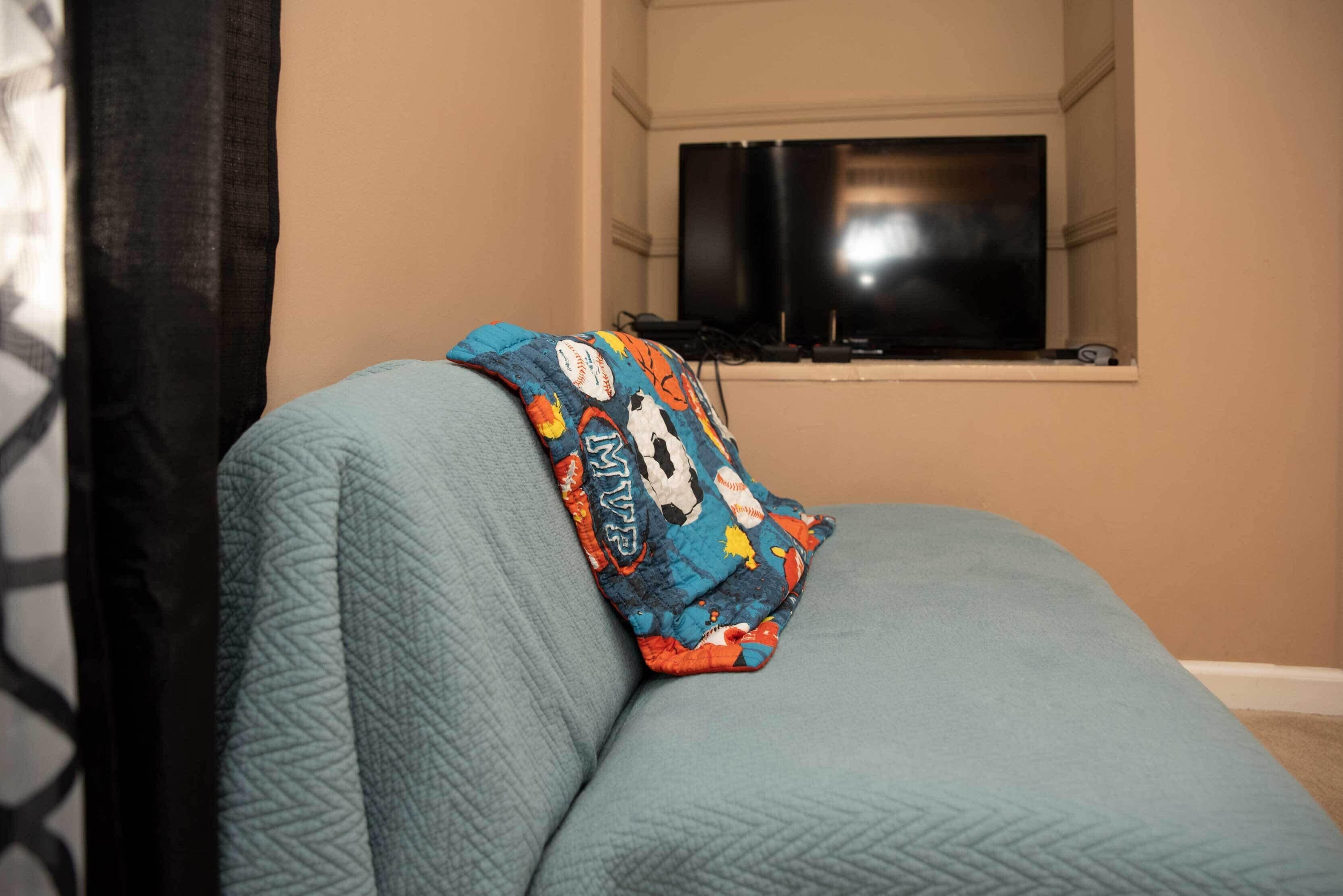 A room with a bed, a window, and a television.