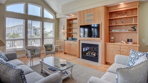 A spacious living room with a fireplace, television, and built-in shelving. - Schmid – Very spacious & elegant home with outstanding ocean and sound views (Wrightsville Beach)