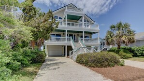 A two-story building with a covered front porch and a garage. - Schmid – Very spacious & elegant home with outstanding ocean and sound views (Wrightsville Beach)