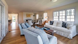 A spacious living room with a white sofa, blue armchairs, and a wooden coffee table. - Luxe Waterfront East Quogue Home w/ Beach On-Site! (East Quogue)