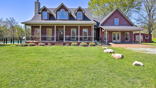 A large two-story house with a wrap-around porch, a chimney, and a well-maintained lawn.