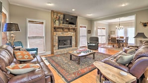 A spacious living room with a stone fireplace, leather sofas, a coffee table, and a chandelier.
