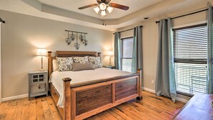 A bedroom with a wooden bed, two bedside lamps, a ceiling fan, and a window with blinds.