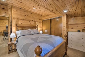 A wooden-paneled bedroom with a bed, dresser, and desk area.