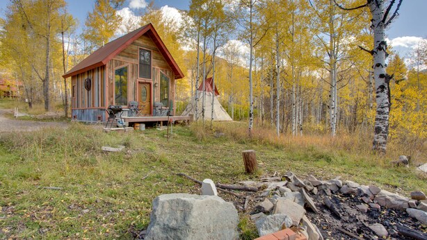 A cabin with a wooden exterior, a porch, and a fire pit area. - Colorful Cabin w/ Teepee, Fire Pits & Mtn Views! (Marble)
