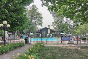 A fenced pool area with a sign indicating pool hours. - Mountain Villa Condo 355 M| Short Walk to Slopes | Community Pool (Boyne Falls)
