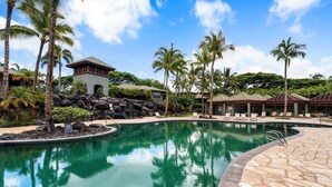 A pool area with clear water, palm trees, and lounge chairs.