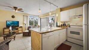 Una cocina moderna con gabinetes blancos, horno empotrado y una isla grande con fregadero.