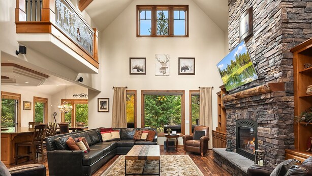 A spacious living room with a fireplace, wooden flooring, and a large sectional sofa. - Luxurious Buttercup Manor in Suncadia! Game Room | Hot Tub | Pet Friendly (Cle Elum)
