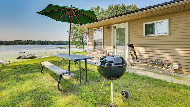 En have med grill, picnicbord og parasol.