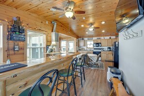A spacious kitchen with wooden cabinets, a central island with bar stools, and a ceiling fan.